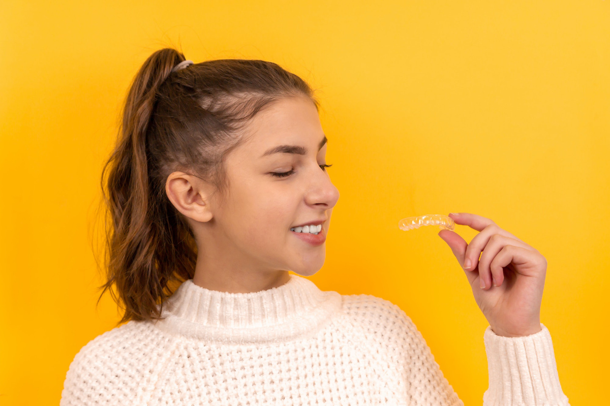 teen girl holding clear removable aligners
